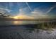 Serene beach scene at sunset with tranquil ocean waters and natural sea grass along the shoreline at 8710 Midnight Pass Rd # 205, Sarasota, FL 34242