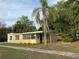 Charming yellow single-story home featuring a purple front door, lush lawn, and tropical landscaping at 1630 29Th St, Sarasota, FL 34234
