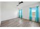 Bright, empty bedroom with a ceiling fan and two windows with turquoise curtains at 6318 Anise Dr, Sarasota, FL 34238