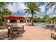 Community pool with brick paver deck, mature palms, shade umbrella and ample seating for residents and guests at 6318 Anise Dr, Sarasota, FL 34238