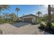 Side view of house showcasing paver driveway, garage, lush lawn and mature landscaping at 1609 Palm View Rd, Sarasota, FL 34240