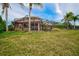 A wide shot of a well-maintained back yard with manicured lawn and screened-in patio against a brilliant blue sky at 2123 Calusa Lakes Blvd, Nokomis, FL 34275