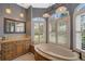 This bathroom has honey wood cabinetry and a corner jacuzzi tub with plantation shuttered windows at 2123 Calusa Lakes Blvd, Nokomis, FL 34275