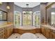 This bathroom has a corner jacuzzi tub under large windows with shutters and honey wood cabinetry at 2123 Calusa Lakes Blvd, Nokomis, FL 34275