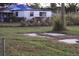 Single-story home with a tarp on the roof surrounded by overgrown grass and sparse landscaping at 2815 Us-41 N, Palmetto, FL 34221