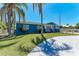 Charming single-story home with a blue exterior, well-manicured lawn, and mature palm trees at 2820 Wood St, Sarasota, FL 34237