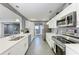 Bright galley kitchen with sleek white cabinets, stainless steel appliances, and tiled floor at 2820 Wood St, Sarasota, FL 34237