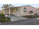 Front view of a manufactured home with carport, steps, and palm tree at 3386 Oakwood N Blvd, Sarasota, FL 34237