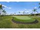 Well-manicured putting green surrounded by palm trees, ideal for practicing your short game in a serene environment at 5107 Coral Reef Way, Bradenton, FL 34211
