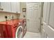 Well-equipped laundry room with bright red washer and dryer, white cabinets, and a utility sink at 6504 Copper Ridge Trl, Bradenton, FL 34201