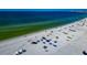 Aerial beach view; white sand, blue water, and beach umbrellas at 915 Seaside Dr # 604, Sarasota, FL 34242