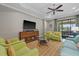 Open living room with a view of the patio, green armchairs, and a large TV at 12606 Fontana Loop, Bradenton, FL 34211