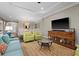 Spacious living room with light teal sofa, green armchairs, and a large TV at 12606 Fontana Loop, Bradenton, FL 34211