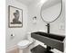 Stylish powder room with a black floating sink and round mirror at 129 Mckinley Dr, Sarasota, FL 34236