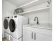 Modern laundry room with white cabinets, shelving, and a utility sink at 129 Mckinley Dr, Sarasota, FL 34236
