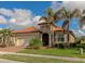 Tan house with a tile roof, two-car garage, and lush landscaping at 24160 Gallberry Dr, Venice, FL 34293