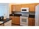 Efficient kitchen featuring light wood cabinets, black countertops, white appliances, and a functional layout for cooking ease at 5115 44Th St W, Bradenton, FL 34210