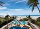Picturesque aerial view showcasing the pool, beach, and palm trees with clear skies, illustrating the beauty of coastal living at 6161 Gulf Of Mexico Dr, Longboat Key, FL 34228