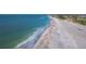 Aerial view of a beach with the gentle surf meeting the sandy shore, showcasing nearby waterfront properties at 6161 Gulf Of Mexico Dr, Longboat Key, FL 34228