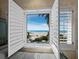 Gorgeous beach view through open plantation shutters, a window seat, and natural light create a relaxing space at 6161 Gulf Of Mexico Dr, Longboat Key, FL 34228