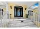 Elegant front entrance featuring a decorative glass door, sconces, and well-manicured landscaping at 6161 Gulf Of Mexico Dr, Longboat Key, FL 34228