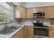 Modern kitchen with stainless steel appliances, blonde cabinets, light countertops, and a stainless sink at 671 47Th St, Sarasota, FL 34234
