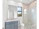 Stylish bathroom with a blue vanity and a glass-enclosed shower with pebble flooring at 8367 Sea Glass Ct, Sarasota, FL 34240