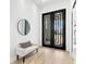 Inviting foyer with sleek black double doors, a modern bench, and a minimalist round mirror at 8367 Sea Glass Ct, Sarasota, FL 34240