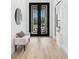 Bright foyer featuring elegant black double doors, a stylish bench, and light wood flooring at 8367 Sea Glass Ct, Sarasota, FL 34240