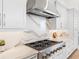 Close-up of a kitchen featuring a modern range hood, stone backsplash, and stainless steel stove at 8367 Sea Glass Ct, Sarasota, FL 34240