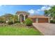 Inviting home featuring a manicured lawn, mature landscaping, and a paver driveway leading to a three-car garage at 2886 Grazeland Dr, Sarasota, FL 34240
