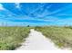 Sandy path through lush dunes leads to a pristine beach, offering a tranquil escape at 506 S Casey Key Rd, Nokomis, FL 34275