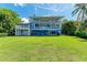 Stunning three-story blue home boasts multiple balconies, a lush lawn, and elegant design at 506 S Casey Key Rd, Nokomis, FL 34275