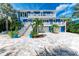 Stunning two-story home with blue siding, white trim, balconies, and a beautiful paver driveway and lush tropical landscaping at 506 S Casey Key Rd, Nokomis, FL 34275