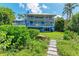 Beautiful three-story home with lush landscaping, a stone pathway, and tranquil outdoor space at 506 S Casey Key Rd, Nokomis, FL 34275