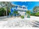 Stunning blue two-story home featuring balconies, lush landscaping, and a stylish paved driveway at 506 S Casey Key Rd, Nokomis, FL 34275