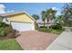 Brick driveway leading to a yellow house with white garage doors at 5759 Benevento Dr, Sarasota, FL 34238