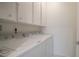 Bright laundry room with full-sized washer and dryer and overhead cabinets at 1800 Benjamin Franklin Dr # A405, Sarasota, FL 34236