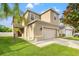 Two-story house with beige exterior, two-car garage, and manicured lawn at 1964 Hawks View Dr, Ruskin, FL 33570