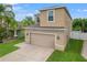 Two-story house with beige exterior, two-car garage, and well-maintained lawn at 1964 Hawks View Dr, Ruskin, FL 33570
