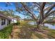 Backyard with lake view, green space, manicured shrubbery, and mature oak tree providing shade at 5436 Hampstead Heath # 25, Sarasota, FL 34235