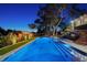 Luxury home with an expansive pool, spa, landscape lighting and mature trees at twilight at 1541 Bay Point Dr, Sarasota, FL 34236