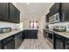 Modern kitchen featuring black cabinetry, stainless steel appliances, and wood-look tile flooring at 2155 Jagust Rd, North Port, FL 34288