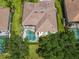 Bird's eye view of a property with a tile roof, private screened-in pool, and lush green surroundings at 2737 Harvest Dr, Sarasota, FL 34240