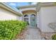 Inviting front entrance with a decorative door, arched windows, and stone walkway lined with lush landscaping at 2737 Harvest Dr, Sarasota, FL 34240
