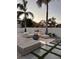 Backyard oasis with modern seating, a fire pit, pavers, and lush landscaping under palm trees at 5906 Larchwood Ave, Sarasota, FL 34231