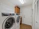 Bright laundry room features modern washer and dryer, upper cabinets, and hardwood floor at 7207 Oak Moss Dr # 63, Sarasota, FL 34241