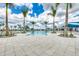 Community pool featuring sun loungers, palm trees, and a spacious pool deck under a partly cloudy sky at 9244 Ballaster Pointe Loop, Parrish, FL 34219