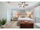 Inviting bedroom with light blue walls, ceiling fan, neutral bedding, and ample natural light at 10379 Medjool Dr, Venice, FL 34293