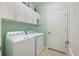 Laundry room with stacked washer and dryer, upper cabinets, and neutral tile flooring at 10379 Medjool Dr, Venice, FL 34293